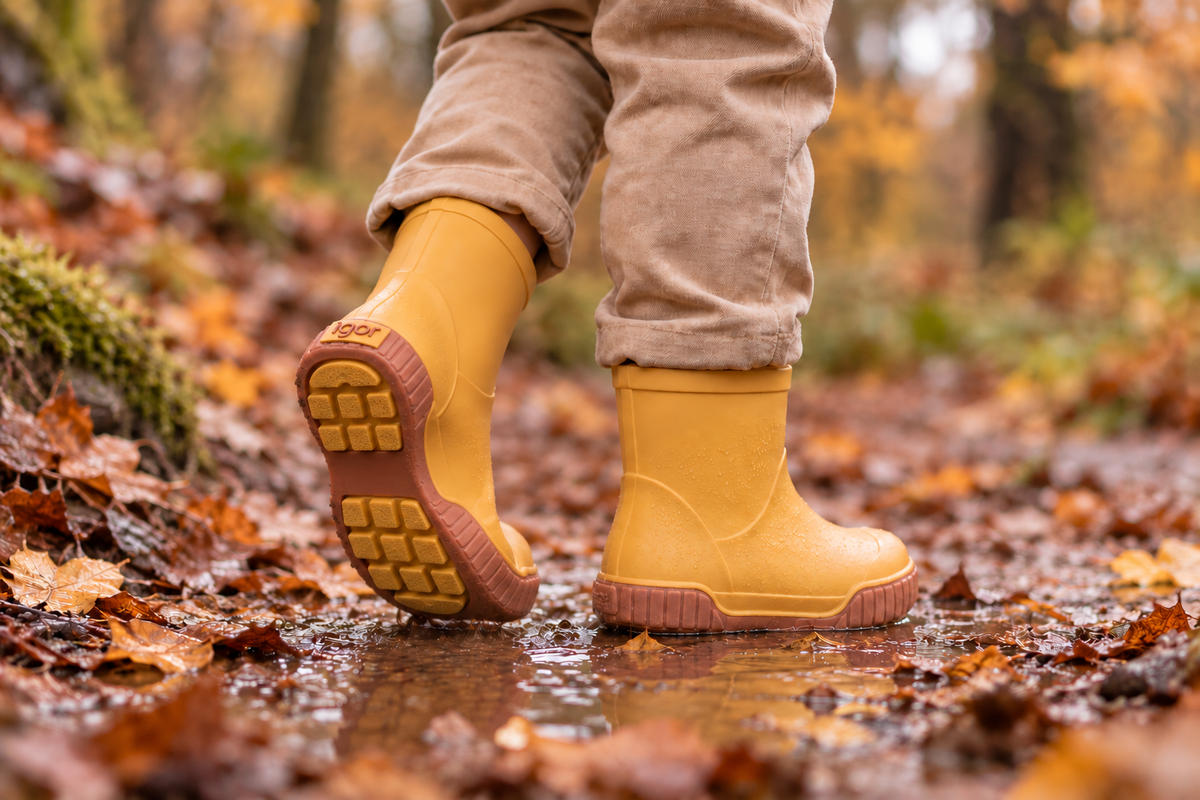 Enfant marchant en forêt sous la pluie avec des bottes barefoot IGOR jaunes souples